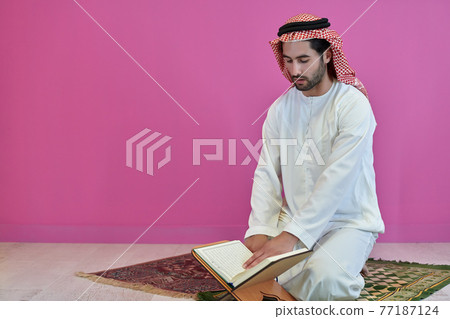 Young muslim man reading Quran during Ramadan 77187124