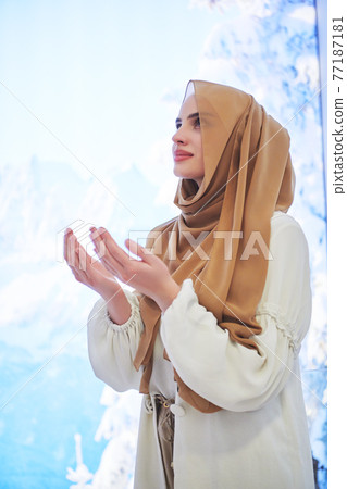 Portrait of young muslim woman praying or making dua to God 77187181