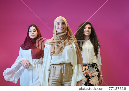 Young muslim women posing on pink background Young muslim women posing on pink background 77187816