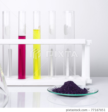 Cosmetic chemicals ingredient on white laboratory table. KMnO4 on chemical watch glass. Potassium Permanganate Liquid and Nickle chloride liquid in test tube in the background. Cosmetic chemicals ingredient on white laboratory table. KMnO4 on chemical watch glass. Potassium Permanganate Liquid and Nickle chloride liquid in test tube in the background. 77187851