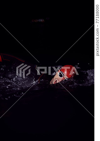 triathlon athlete swimming in dark night wearing wetsuit 77188000