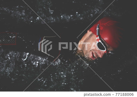triathlon athlete swimming in dark night wearing wetsuit 77188006