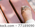 Toddler's feet playing in the sandbox 77189090