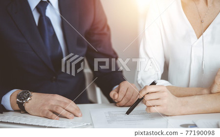 Unknown businessman and woman discussing contract in sunny office, close-up.Business people or lawyers working together at meeting Unknown businessman and woman discussing contract in sunny office, close-up.Business people or lawyers working together at meeting 77190098