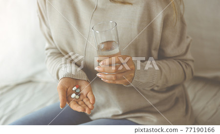 Close-up woman holding pills time to take medications, cure for headache. Medicine concept during self isolation and Coronavirus pandemic Close-up woman holding pills time to take medications, cure for headache. Medicine concept during self isolation and Coronavirus pandemic 77190166