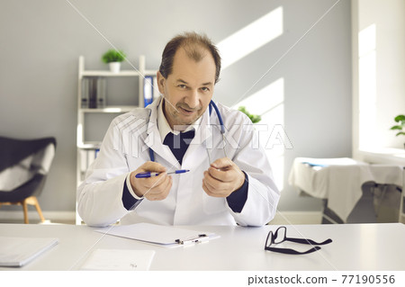 Doctor at desk consulting patient online explaining prescription to camera 77190556