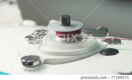 Close-up photo of spinning bobbin of thread Close-up photo of spinning bobbin of thread 77190575