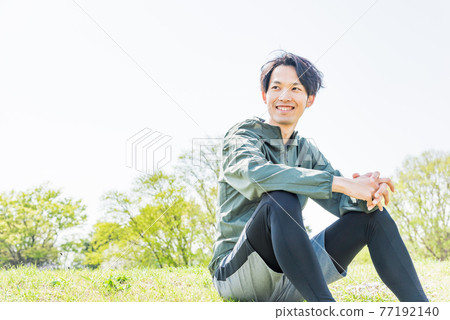 A young man taking a break in the park while running A young man taking a break in the park while running 77192140