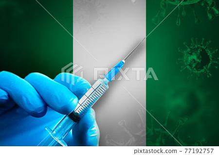 Nigeria Covid-19 Vaccination Campaign. Hand in a blue rubber glove holds a syringe with covid-19 virus vaccine in front of Nigeria flag 77192757