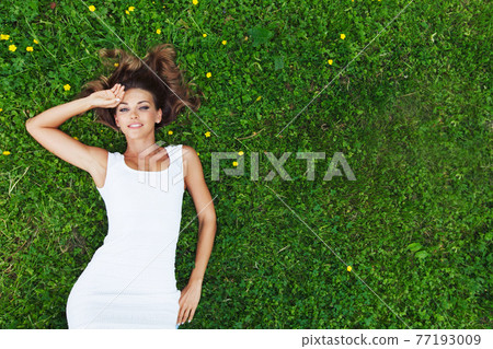 Woman in white dress lying on grass Woman in white dress lying on grass 77193009