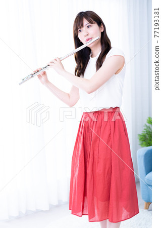 Woman playing the flute in the room Woman playing the flute in the room 77193181