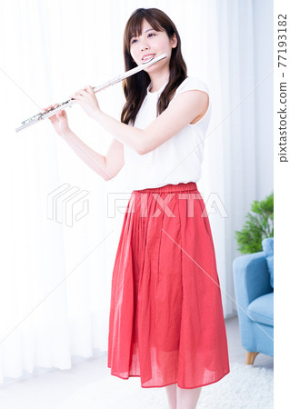 Woman playing the flute in the room Woman playing the flute in the room 77193182
