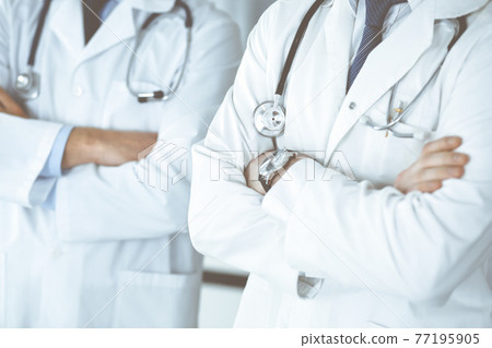 Group of unknown doctors standing as a team with arms crossed in hospital office, close-up. Medical help, insurance in health care and medicine concept Group of unknown doctors standing as a team with arms crossed in hospital office, close-up. Medical help, insurance in health care and medicine concept 77195905