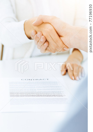 Casual dressed businessman and woman shaking hands after contract signing in sunny office. Handshake concept Casual dressed businessman and woman shaking hands after contract signing in sunny office. Handshake concept 77196930