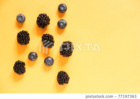 Blackberries and blueberries on a yellow background with copy space Blackberries and blueberries on a yellow background with copy space 77197363