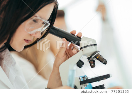 close up.the scientist looks into the microscope in the laborat close up.the scientist looks into the microscope in the laborat 77201365