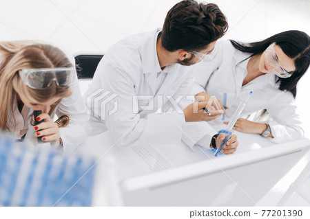 close up. a group of scientists conduct research and make entri 77201390