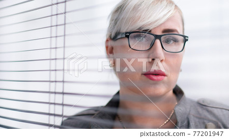 close up. business woman looks somewhere through the office window. 77201947