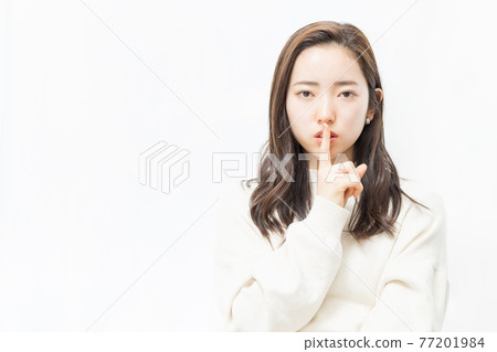 A woman who raises her index finger in front of her mouth (quietly) 77201984