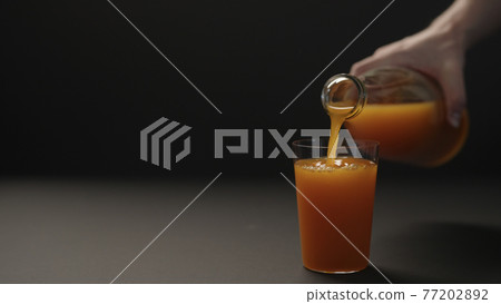 man hand pour mango juice into tumbler glass on black paper background with copy space man hand pour mango juice into tumbler glass on black paper background with copy space 77202892
