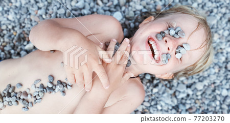 On sunny beach kids lying on pebble, warming after swimming 77203270