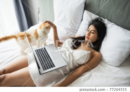 Young sexy woman watch movie with cat on bed Young sexy woman watch movie with cat on bed 77204555