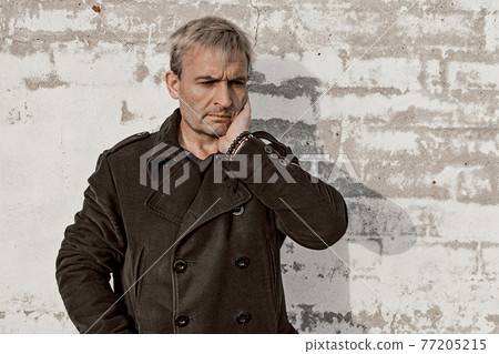 Middle aged blonde caucasian man in trendy clothes is posing in front of a white brick wall. Male fashion photoshoot. Men's mental health. Emotions. Front view, copy space. Middle aged blonde caucasian man in trendy clothes is posing in front of a white brick wall. Male fashion photoshoot. Men's mental health. Emotions. Front view, copy space. 77205215