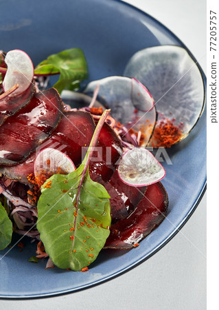 Beet summer salad with arugula, radicchio, soft cheese and walnuts on plate dressing and spices on blue plate, copy space, top view Beet summer salad with arugula, radicchio, soft cheese and walnuts on plate dressing and spices on blue plate, copy space, top view 77205757