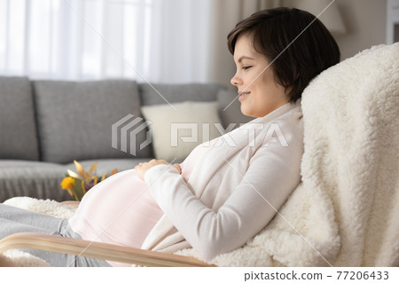 Happy pregnant woman relax in chair at home Happy pregnant woman relax in chair at home 77206433