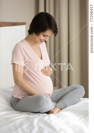 Smiling pregnant woman touch caress baby bump 77206457