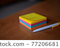 A pack of multicolored papers and a white pencil on a wooden board. 77206681