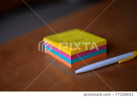 A pack of multicolored papers and a white pencil on a wooden board. A pack of multicolored papers and a white pencil on a wooden board. 77206681