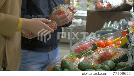 Man and woman buying vegetables in the supermarket 77209693