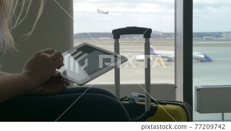 Woman waiting for the flight with tablet PC Woman waiting for the flight with tablet PC 77209742