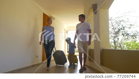Family with rolling bags in hotel corridor Family with rolling bags in hotel corridor 77209744