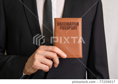 Vaccination Passport. Businessman showing passport covers. Travel concept 77209817