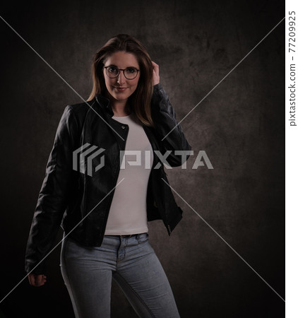 Close-up of a young attractive woman against dark grey background Close-up of a young attractive woman against dark grey background 77209925