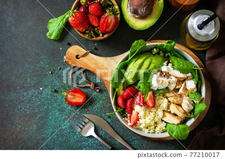 Healthy food, diet lunch menu concept, ketogenic diet and paleo diet. Couscous salad with strawberries, grilled chicken, avocado and feta cheese on a stone table.  77210017