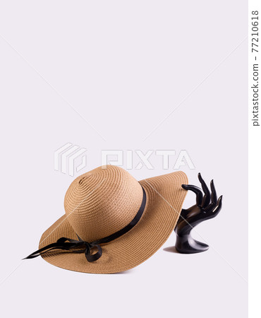 Black Plastic hand the mannequin holding fashion summer straw hat against light gray background. Good for summer sale or tour announcement backdrop. 77210618
