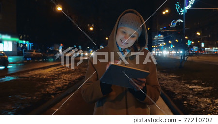 Evening walk in the city with tablet computer 77210702