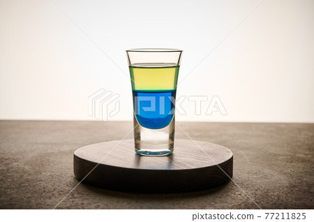 Homemade yellow and blue transparent alcohol drink in glass of limoncello and curacao Homemade yellow and blue transparent alcohol drink in glass of limoncello and curacao 77211825