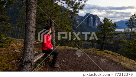 Adventurous Woman Hiking in the mountains during a Spring Sunset 77212379