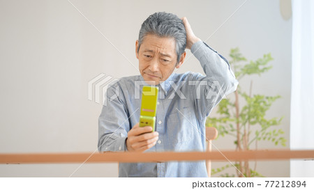 努力操作手機的老人 77212894