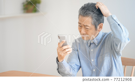 努力操作智能手機的老人 77212908