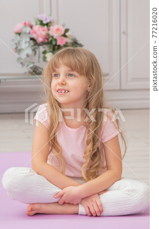 Full length front view cute little preschool girl sitting on on yoga mat 77216020