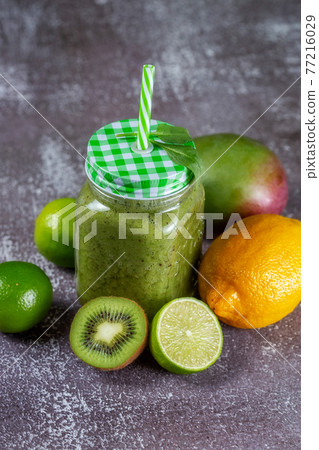 Healthy fresh fruit smoothie drink surrounded by kiwi lime and lemon on gray 77216029