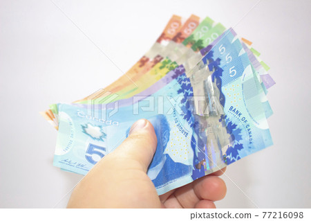 Calgary, Alberta. Canada. April 02, 2021. A person holding canadian bank notes bills. 77216098