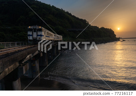 A train that runs along the coast in response to the sunrise in the thin clouds 77216117