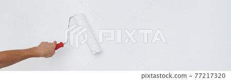 Man painting wall with paint roller Man painting wall with paint roller 77217320