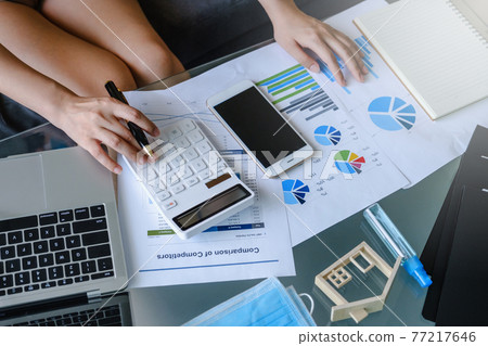 Close up Business woman using calculator and laptop for do math finance on wooden desk work from home concept 77217646